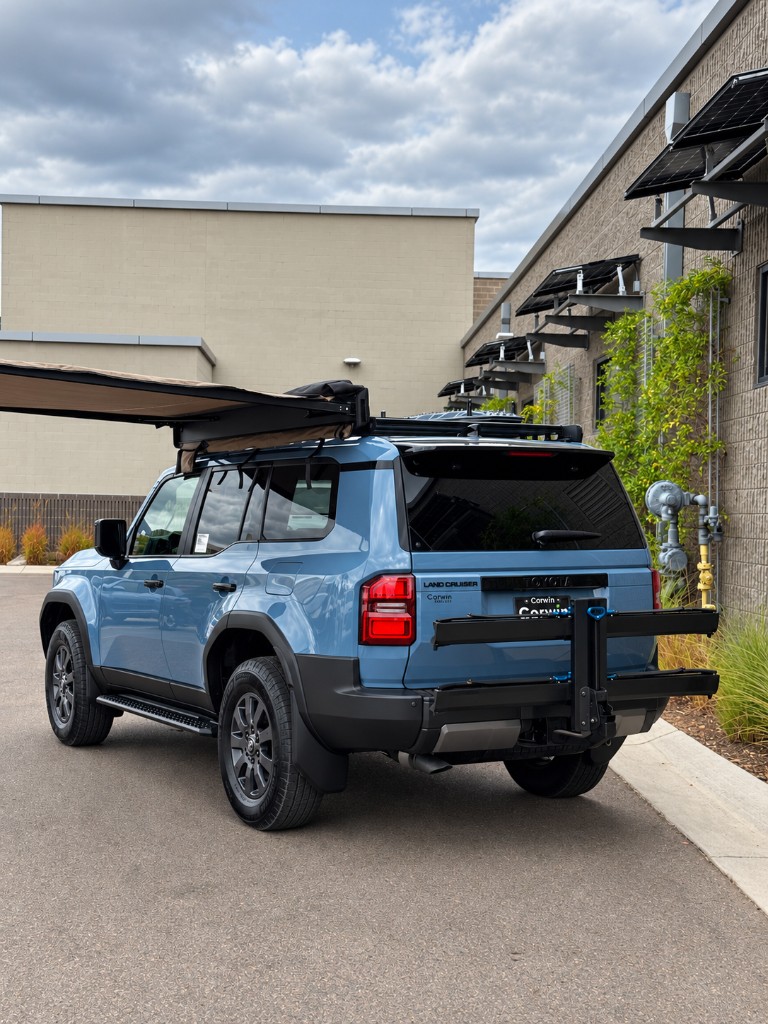 Rear three-quarter view of the Land Cruiser with awning and bike rack