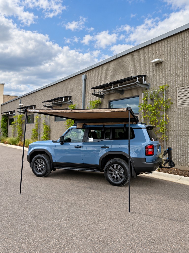 Side view of the Land Cruiser with awning, roof rack, and hitch bike rack